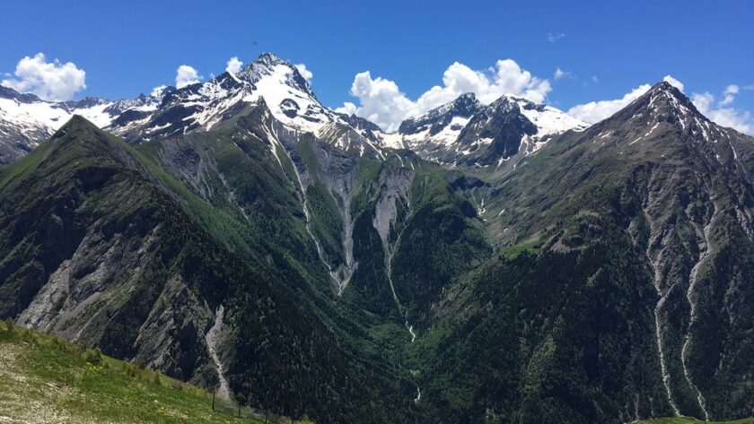 Panorama estival des montagnes des 2 Alpes avec sommets enneigés, vallées verdoyantes et ciel bleu