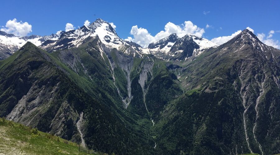Panorama estival des montagnes des 2 Alpes avec sommets enneigés, vallées verdoyantes et ciel bleu