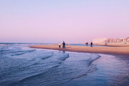 Famille se promenant au coucher du soleil sur la plage de sable de Malo-les-Bains à Dunkerque