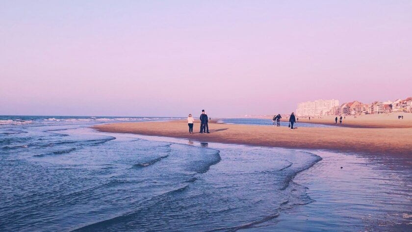 Famille se promenant au coucher du soleil sur la plage de sable de Malo-les-Bains à Dunkerque