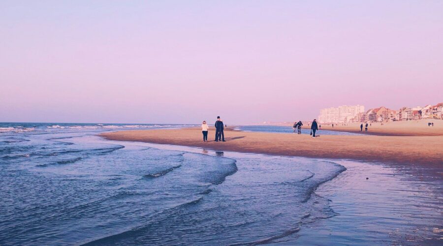 Famille se promenant au coucher du soleil sur la plage de sable de Malo-les-Bains à Dunkerque