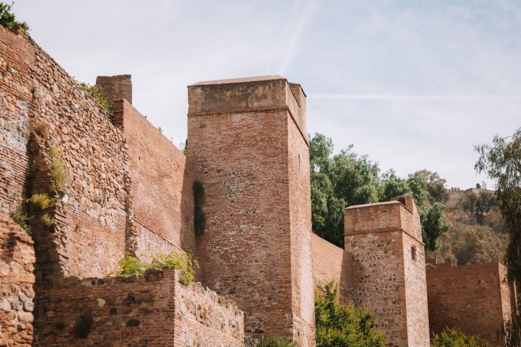 Murailles en brique et tours de fortification de la citadelle de l'Alcazaba à Malaga sous un ciel dégagé.
