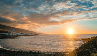 Coucher de soleil ensoleillé sur une plage et la côte de Tenerife aux îles Canaries