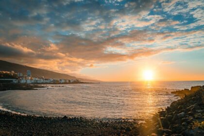 Coucher de soleil ensoleillé sur une plage et la côte de Tenerife aux îles Canaries